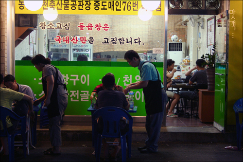 손님들이 곱창을 안주삼아 한 잔 하고 있다 